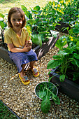 Mädchen erntet Spinat im Kinderanbaugebiet