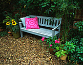 Designer Clare MATTHEWS: CHILDRENS Party - GRAVEL Garden REDAY FOR Party with Blue BENCH, Pink CUSHION AND Container with SUNFLOWERS