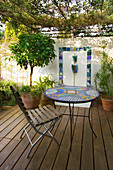 MEDITERRANEAN DECKED COURTYARD with STANDARD Bay, TILED Water Feature AND MOSAIC TABLE. SHADE CANOPY. DECKING, TRELLIS, VINE, KATHY Taylor'S Garden, London