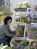 Woman decorates white shelf with spring flowers