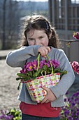 Girl with Primula acaulis (primroses) in wicker bag