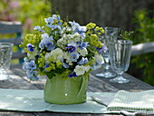 Early summer bouquet in a green milk jug: Dianthus (carnations), Viola cornuta
