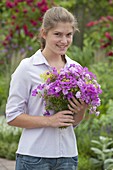 Young woman with bouquet of Geranium (cranesbill), Dianthus (carnations)