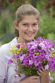 Young woman with bouquet of geranium (cranesbill), dianthus (carnations)