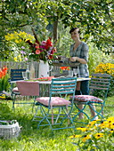 Table with gladiolus-dahlia bouquet under apple tree