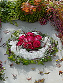 Grave wreath with pink (roses) in a flower wreath made of plaster, decorated with Calluna