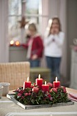 Adventskranz aus Ilex (Stechpalme) mit roten Kerzen, Äpfeln und Zieräpfeln