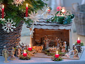 Small nativity scene next to Christmas tree, straw stars, red candles