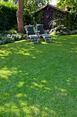 Liegen im Schatten unter großem Baum, Gartenhaus, Beete mit Schattenstauden