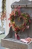Herz aus Moos und Rosa (Hagebutten), dekoriert mit angedrahteten Blättern
