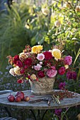 Bouquet of mixed pinks (roses) and rose hips in rustic vase