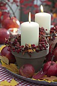 Autumnal candle decoration with white candles in clay pots