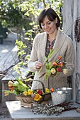 Woman ties bouquet of Tulipa (tulips) and Salix (willow catkins)