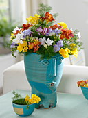 Colourful scented bouquet of freesia (freesia) in handmade pot with face