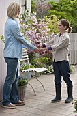 Girl giving mother bouquet of Prunus sargentii 'Accolade'
