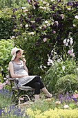 Schwangere Frau genießt den Duft im Rosengarten
