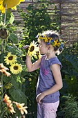 Girl with wreath on her head sniffing Helianthus