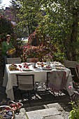 Herbstlich gedeckter Tisch mit Äpfeln (Malus), Sträusse aus Rosa