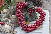 Heart of ornamental apples leaning against firewood, small glass as a lantern