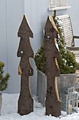 Stilisierte Weihnachtsbäume aus Brettern mit Rinde ausgeschnitten