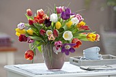 Bunter Strauss mit farblich gemischten Tulipa (Tulpen) in Glas-Vase