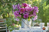 Table under the apple tree with a bouquet of summer flowers