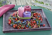 Autumnal wreath of wild fruits on a wooden coaster