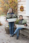 Kinder mit Metall-Jardinierer mit Calluna vulgaris Garden Girls
