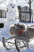Verschneiter Garten mit Schneemann und Schlitten