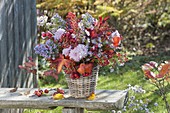 Autumn bouquet with perennials and fruits in basket vase