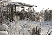 Pavillon im verschneiten Garten, Beete mit Stauden