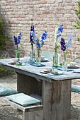 Laid table with delphinium (larkspur) in bottles
