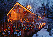 Haus und Gartenzaun mit Weihnachtsbeleuchtung