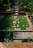 Vorgarten mit gemauerten Beeteinfassungen aus Backsteinen und Trittplatten als Weg im Rasen, Buxus (Buchs - Staemmchen)