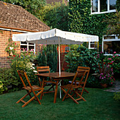 Sitzplatz mit Sonnenschirm im Rasen neben Terrasse