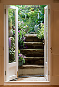 Blick aus dem Küchenfenster auf Treppe mit Töpfen mit Stiefmütterchen und Primula