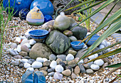 Steine und blaue Keramik als Wasserspeier arrangiert