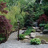 Garten im japanischen Stil: Bambus-Gittertor mit Wasserfall im Hintergrund