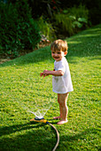 WILLIAM PLAYING with A HOSEPIPE IN THE GARDEN. THE NICHOLS Garden, READING