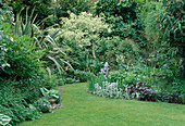 Garten mit Rasen und Beeten mit Iris (Schwertlilie) und Phormium (Neuseeländischer Flachs)