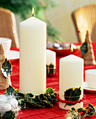 Candles decorated with holly leaves and flowers