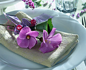 Napkin decoration with Alyogyne huegelii, purple ribbon and pearls