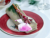 Serviette weihnachtlich dekoriert mit Cyclamenblüte, Zimtstange, Kiefernzweig