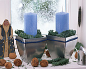 Fensterbankdekoration mit blauen Kerzen und silbernen Töpfen mit Nikolaus