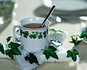 Tischdeko mit Hedera (Efeu), Teetasse mit Wattestern und Efeu geschmückt