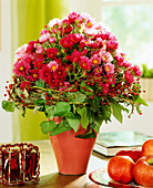 Vase mit Herbstastern und Kranz aus Efeu