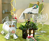 Table decoration for the turn of the year, lucky pig made of clay pots painted silver, hat with feather