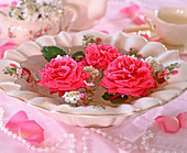 Schale mit Rosenmotiv und schwimmende Rosenblüten