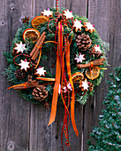 Door wreath made of twigs, cinnamon stars, cinnamon sticks, cones and ribbons