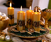 Teller mit goldenen Kerzen, getrockneten Limetten und Nadeln von Nordmanntanne